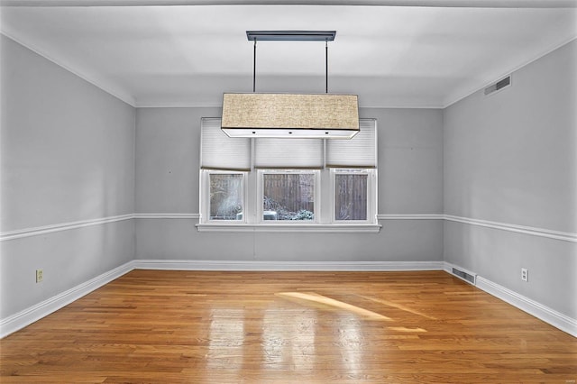 spare room with visible vents, baseboards, and wood finished floors