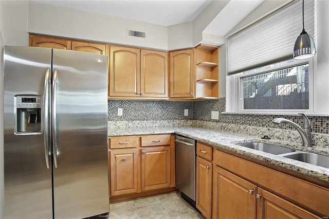 kitchen featuring stainless steel fridge, visible vents, light stone counters, brown cabinets, and a sink