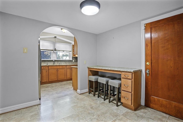 office area with arched walkways, a sink, and baseboards