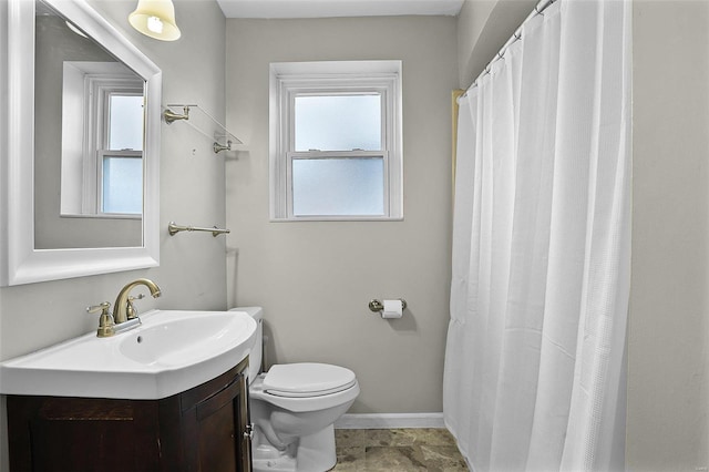 bathroom featuring toilet, baseboards, a wealth of natural light, and vanity