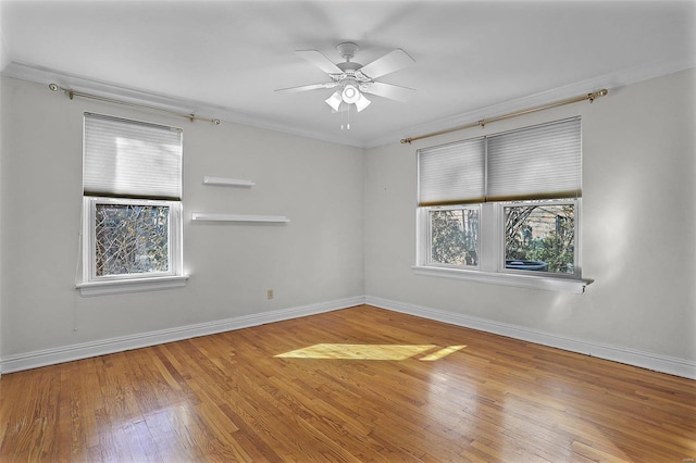 spare room featuring baseboards, ceiling fan, hardwood / wood-style flooring, and crown molding