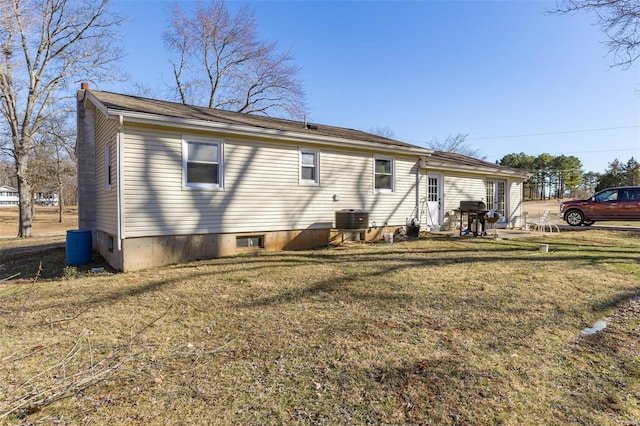 rear view of property with cooling unit and a lawn