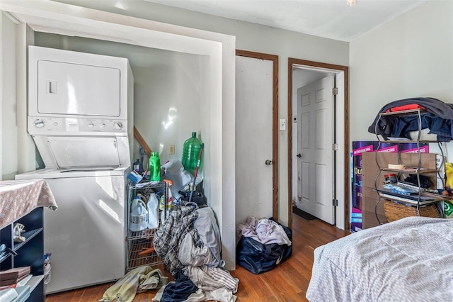 laundry room featuring laundry area, wood finished floors, and stacked washer and clothes dryer