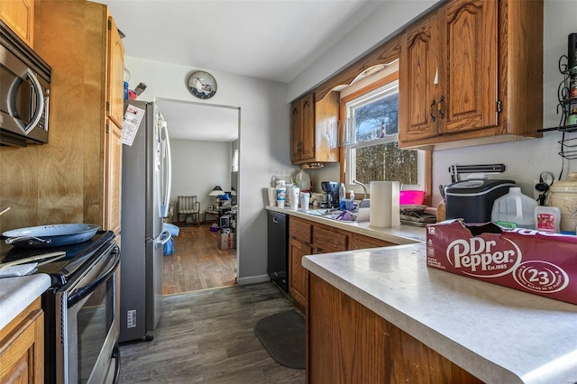 kitchen with stainless steel appliances, light countertops, dark wood-style flooring, and brown cabinets