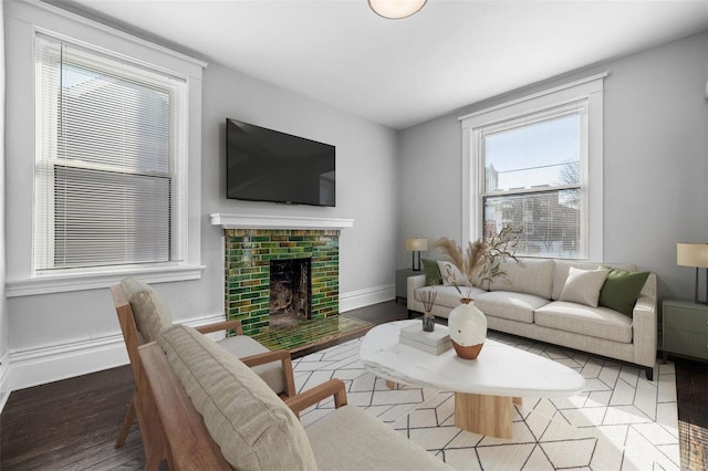 living room featuring a fireplace, baseboards, and wood finished floors