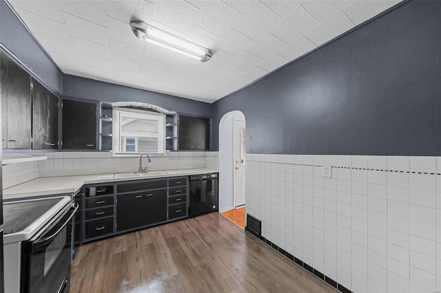 kitchen with arched walkways, black dishwasher, electric stove, a sink, and dark cabinetry