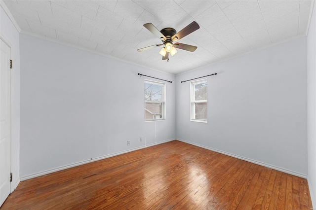 spare room featuring baseboards, a ceiling fan, wood finished floors, and ornamental molding