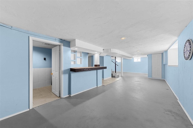 basement with baseboards and a textured ceiling