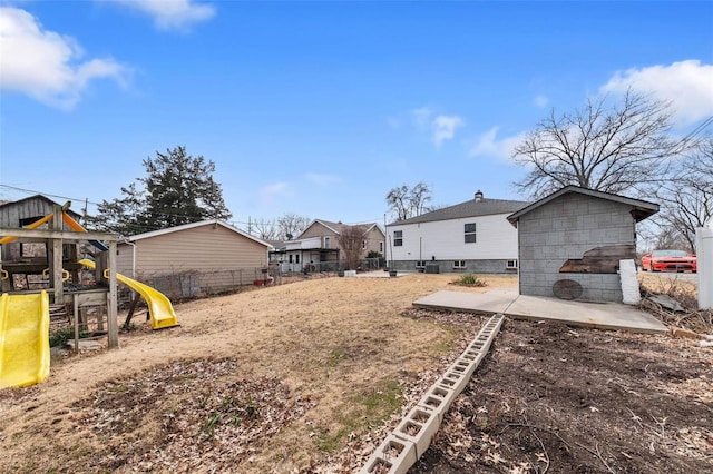 view of yard featuring a patio area, a playground, and fence