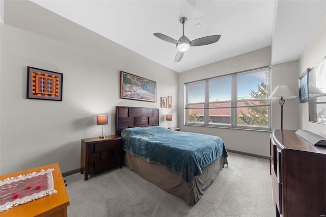 bedroom featuring light carpet, ceiling fan, multiple windows, and baseboards