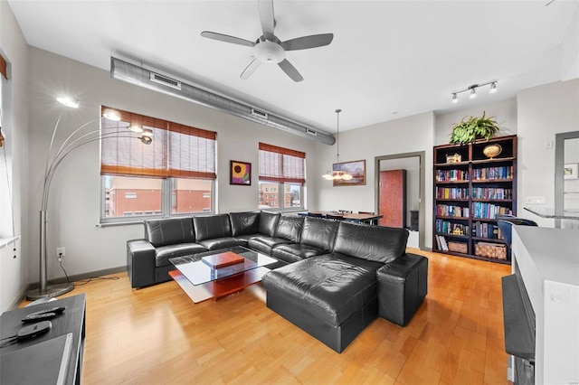 living area with light wood-type flooring, ceiling fan, and visible vents