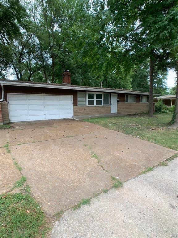 ranch-style house featuring a garage, driveway, and a chimney