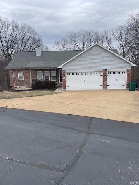 single story home with an attached garage, concrete driveway, and brick siding