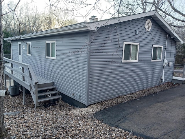 view of side of home featuring a chimney, a wooden deck, and central AC unit