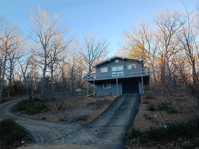 view of side of home with aphalt driveway, a garage, and a wooden deck