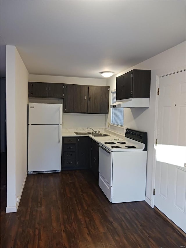 kitchen featuring white appliances, dark wood-type flooring, a sink, and light countertops