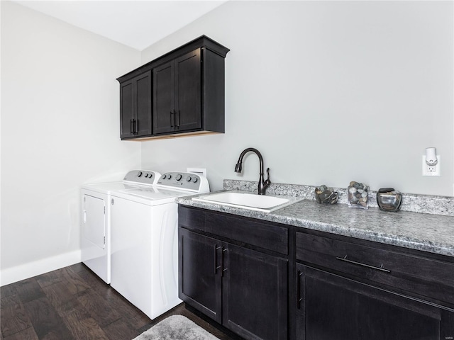 clothes washing area featuring dark wood-style floors, baseboards, cabinet space, separate washer and dryer, and a sink