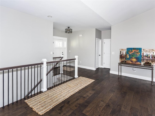 corridor with an upstairs landing, baseboards, and wood finished floors