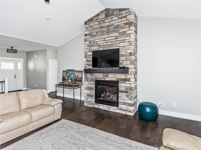 living area featuring vaulted ceiling, a stone fireplace, baseboards, and wood finished floors