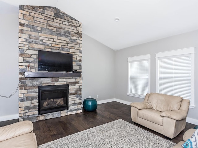 living room featuring a stone fireplace, lofted ceiling, wood finished floors, and baseboards