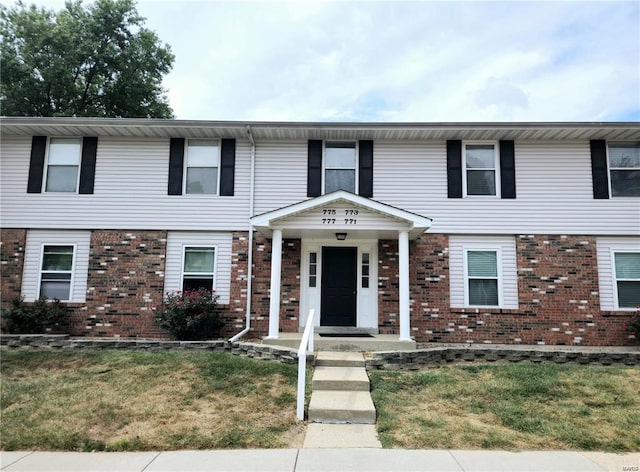 townhome / multi-family property featuring a front lawn and brick siding