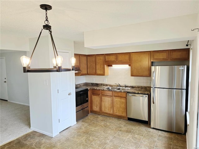 kitchen with stainless steel appliances, a sink, decorative backsplash, brown cabinets, and dark countertops