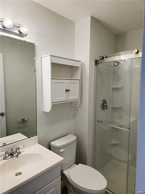 bathroom with a shower stall, toilet, and a textured ceiling