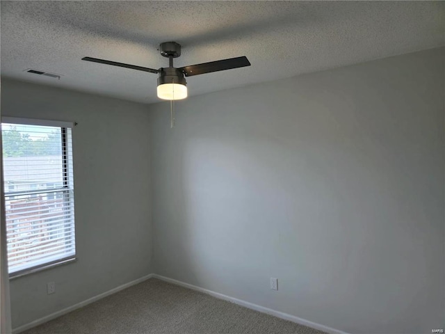 carpeted empty room with visible vents, plenty of natural light, a textured ceiling, and baseboards