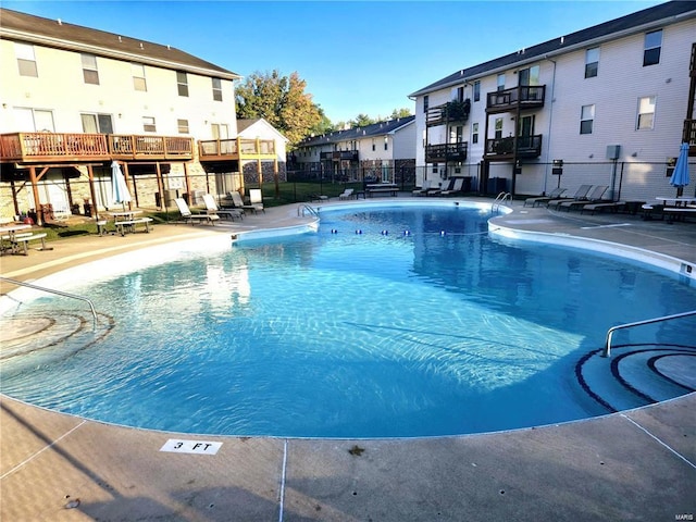 community pool featuring a residential view, fence, and a patio