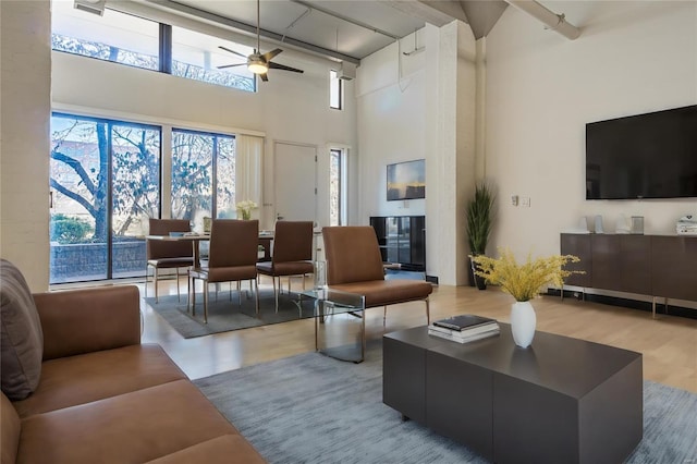 living room featuring a high ceiling, wood finished floors, and a ceiling fan