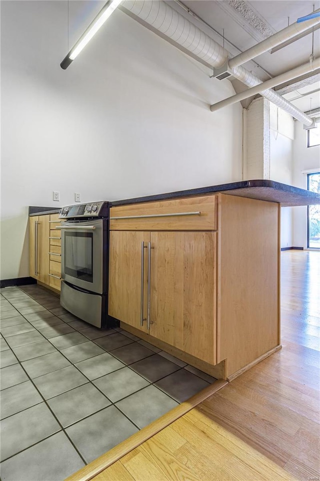 kitchen with stainless steel range with electric stovetop, dark countertops, and light wood-type flooring