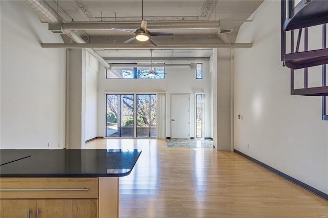 entrance foyer with ceiling fan, light wood finished floors, a towering ceiling, and baseboards