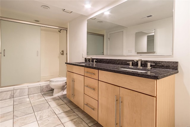 bathroom featuring a sink, a shower stall, toilet, and double vanity