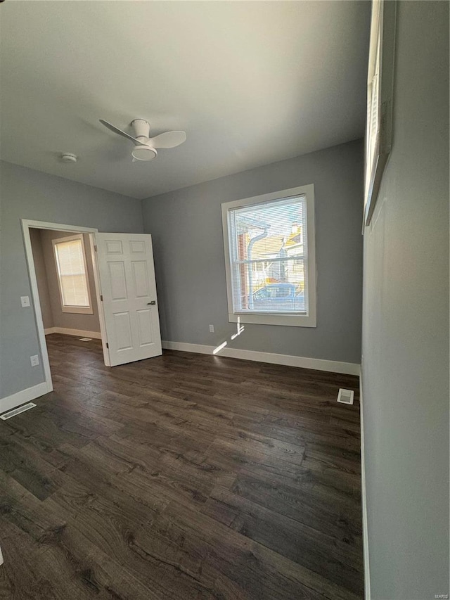 unfurnished bedroom with dark wood-style floors, multiple windows, and baseboards