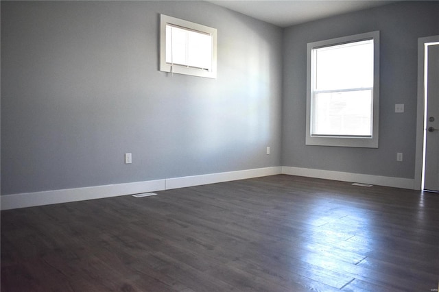 spare room with baseboards and dark wood finished floors