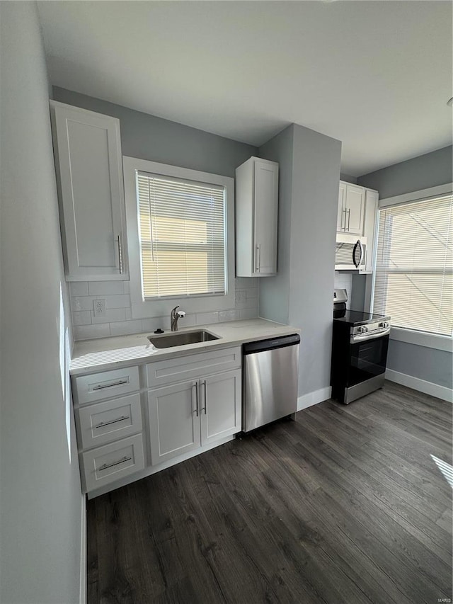 kitchen featuring stainless steel appliances, backsplash, dark wood-type flooring, white cabinets, and a sink