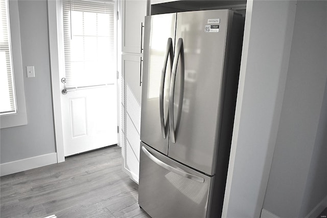 kitchen featuring light wood finished floors, freestanding refrigerator, and baseboards