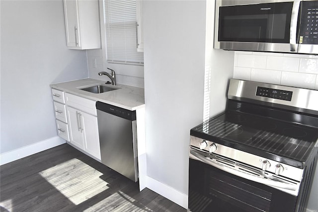 kitchen with decorative backsplash, dark wood-style flooring, stainless steel appliances, white cabinetry, and a sink