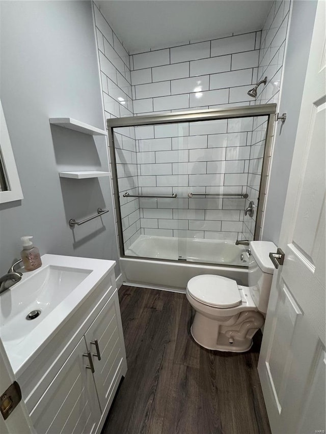 bathroom with toilet, enclosed tub / shower combo, wood finished floors, and vanity