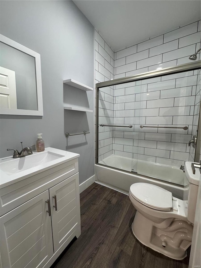 full bathroom featuring baseboards, toilet, enclosed tub / shower combo, wood finished floors, and vanity