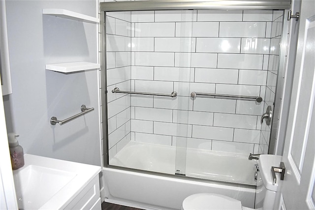 bathroom featuring toilet and shower / bath combination with glass door