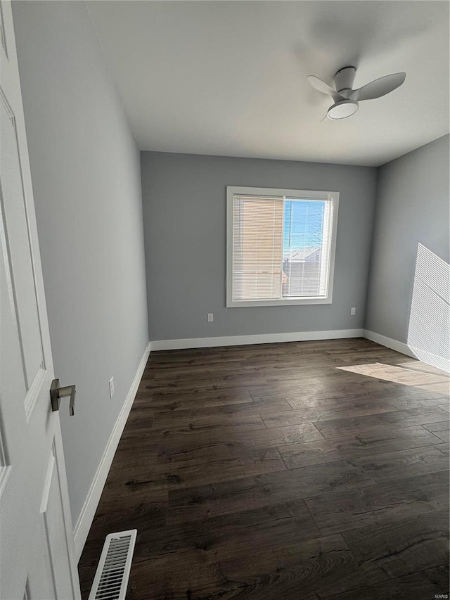 empty room with visible vents, dark wood finished floors, and baseboards