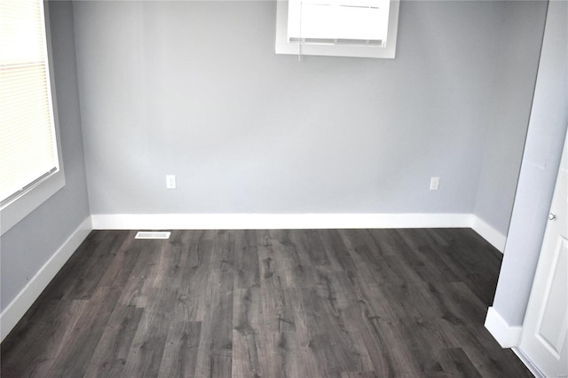 unfurnished room featuring visible vents, baseboards, and dark wood-type flooring