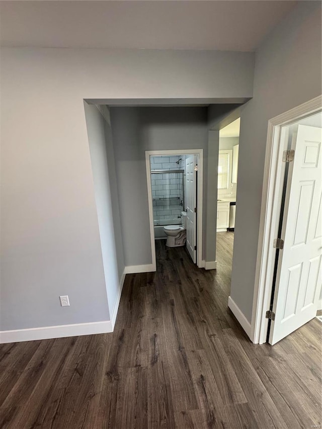 hallway featuring dark wood-type flooring and baseboards