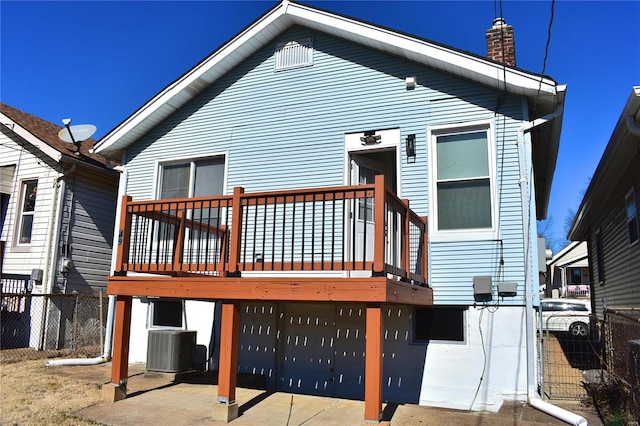 rear view of property with a chimney, fence, a deck, and central AC unit