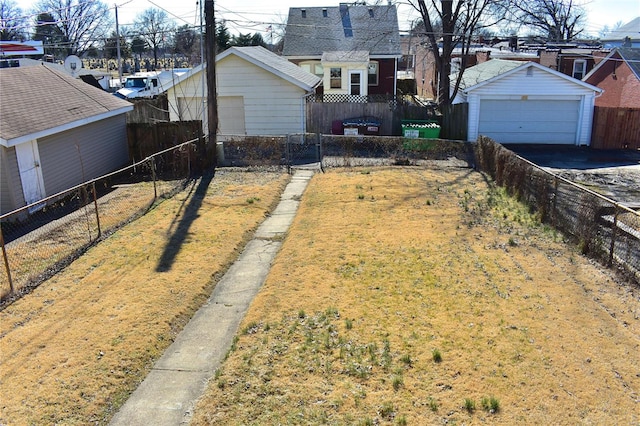 view of yard with a garage, a fenced backyard, and an outbuilding