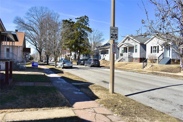 view of road with entry steps, a residential view, curbs, traffic signs, and sidewalks