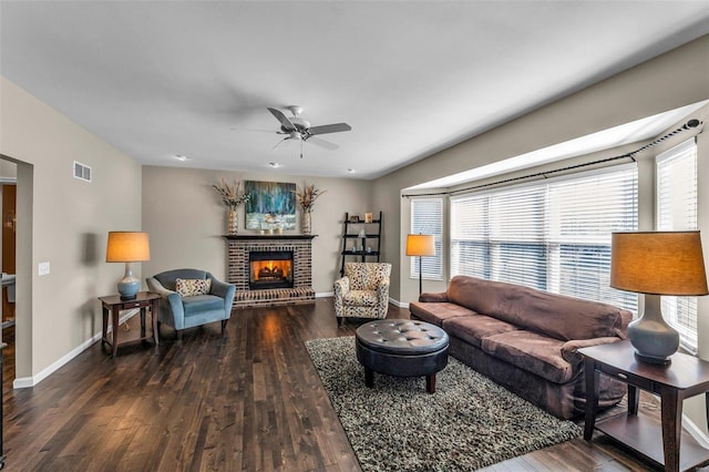 living room featuring visible vents, a fireplace, baseboards, and wood finished floors