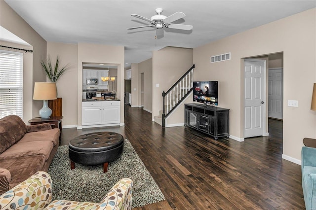 living area with dark wood-style flooring, visible vents, baseboards, and stairs