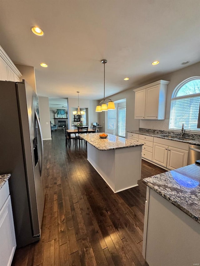 kitchen featuring appliances with stainless steel finishes, dark wood-style flooring, a sink, and white cabinetry